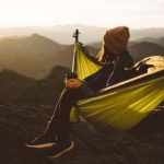 Hiking Times - Unrecognizable woman sitting in hammock above mountains